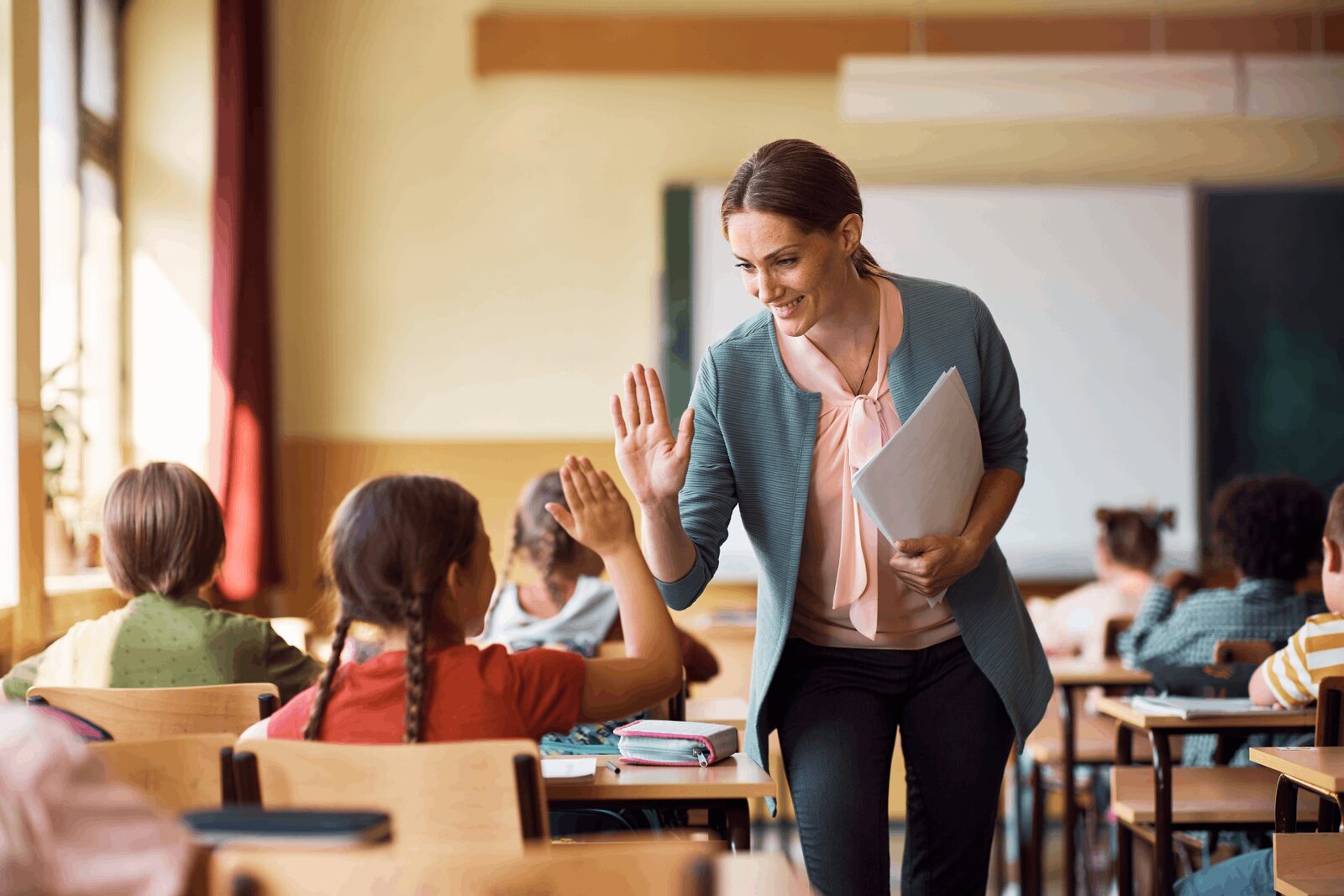 Trainer standing beside desks and speaking with a class of learners