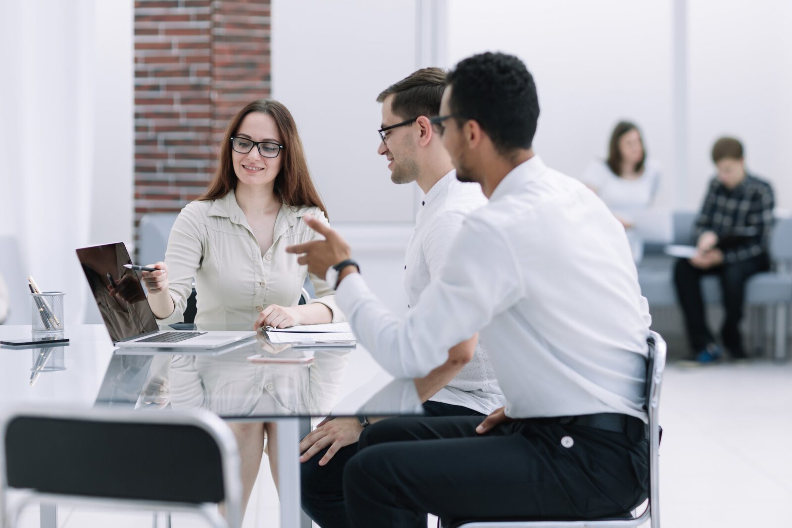 Two consultants discussing documents with a client at an office desk